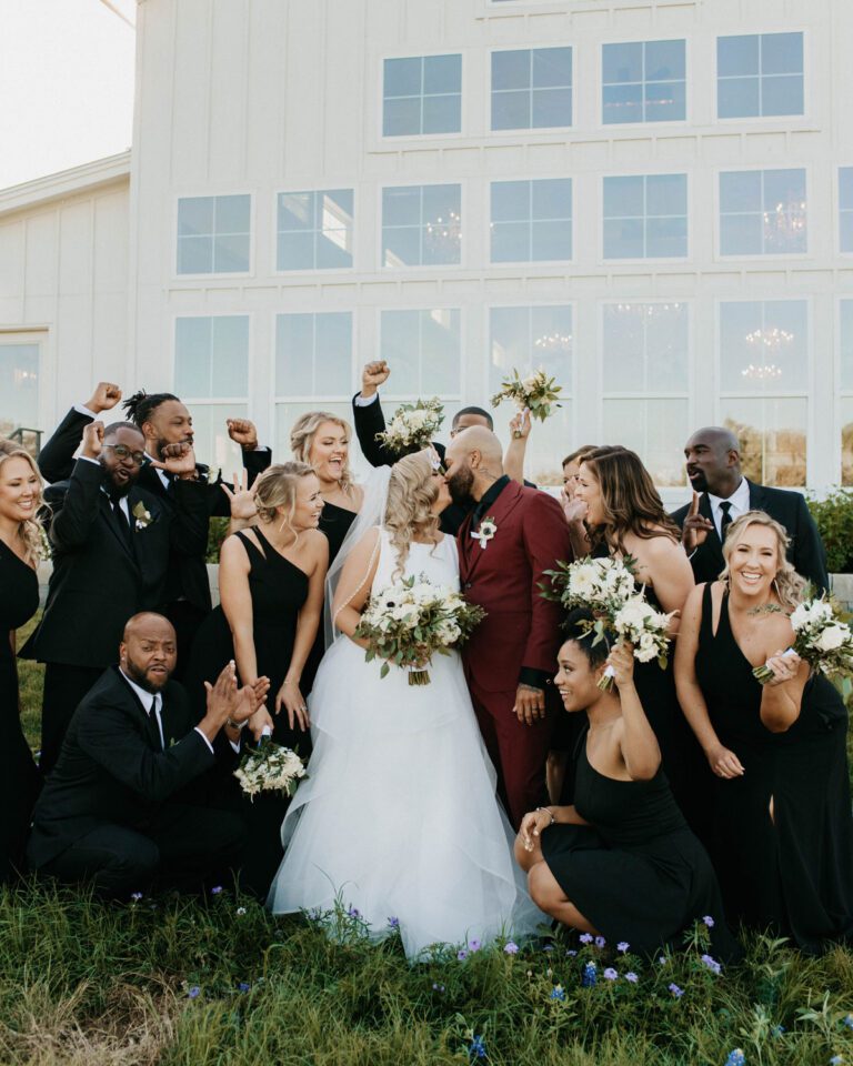 A joyful wedding party posing for a fun and energetic group photo.