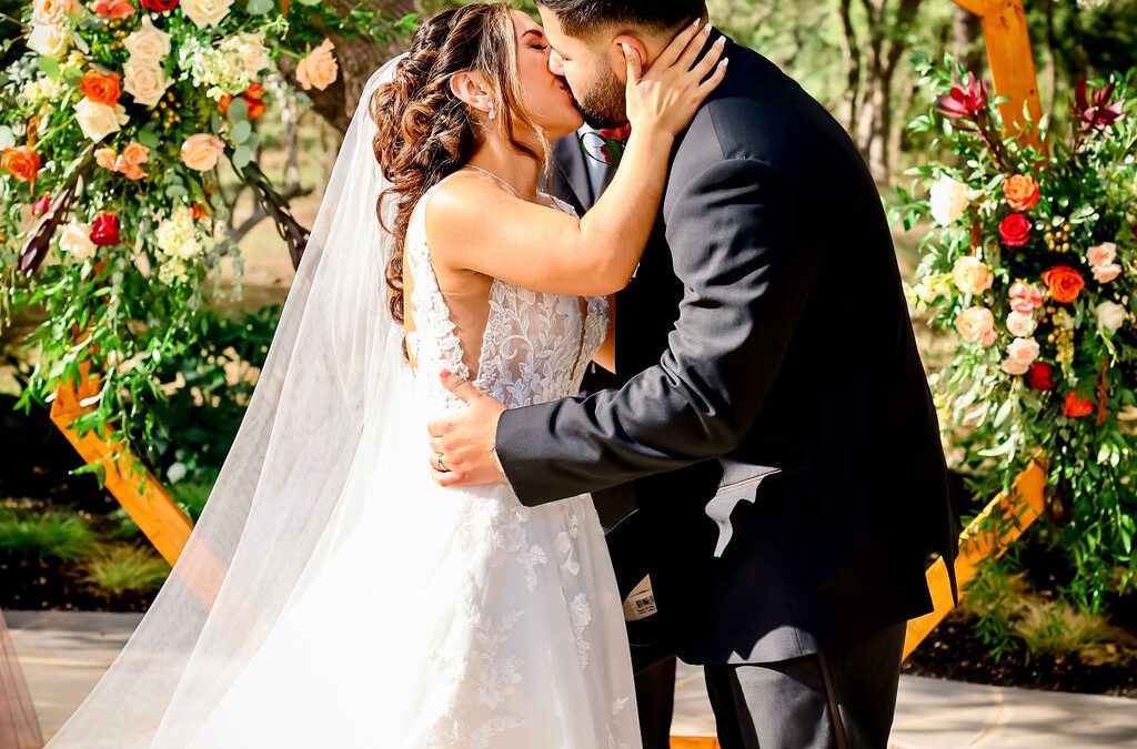 Kissing in front of a geometric wedding arch.