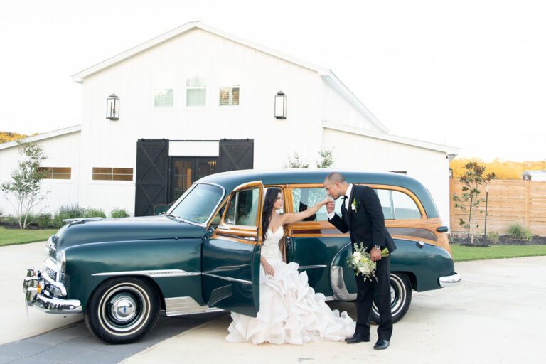 A bride and groom entering their vintage car decorated for the drive away from their wedding reception.